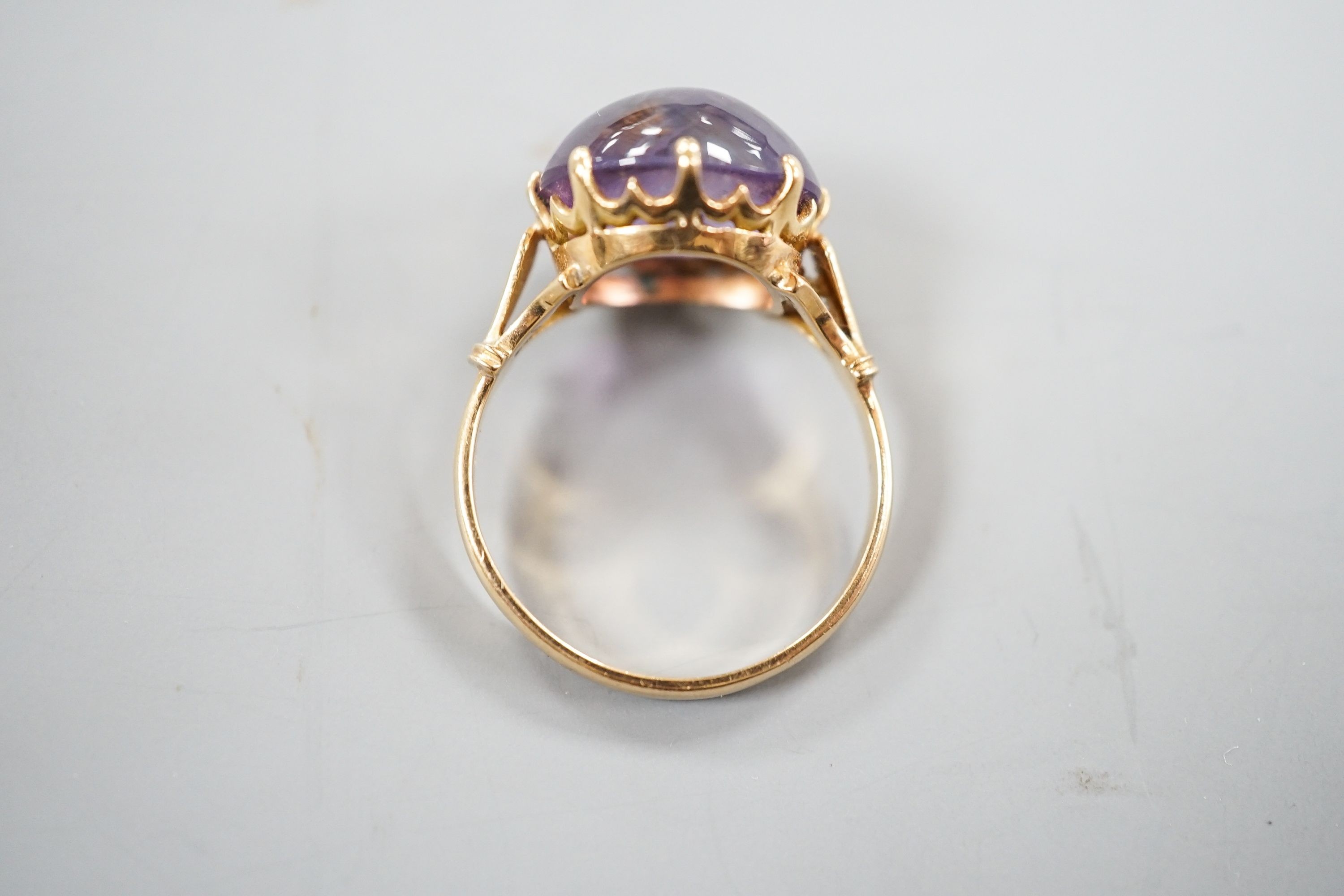 An early 20th century yellow metal and button shaped cabochon amethyst set ring, size R/S, gross weight 5.5 grams.